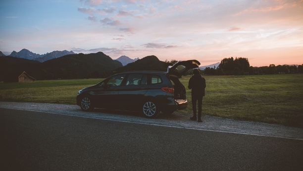 BMW s otevřeným kufrem stojící na kraji silnice