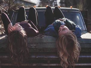 Girls laying next to each other at the hood of a car